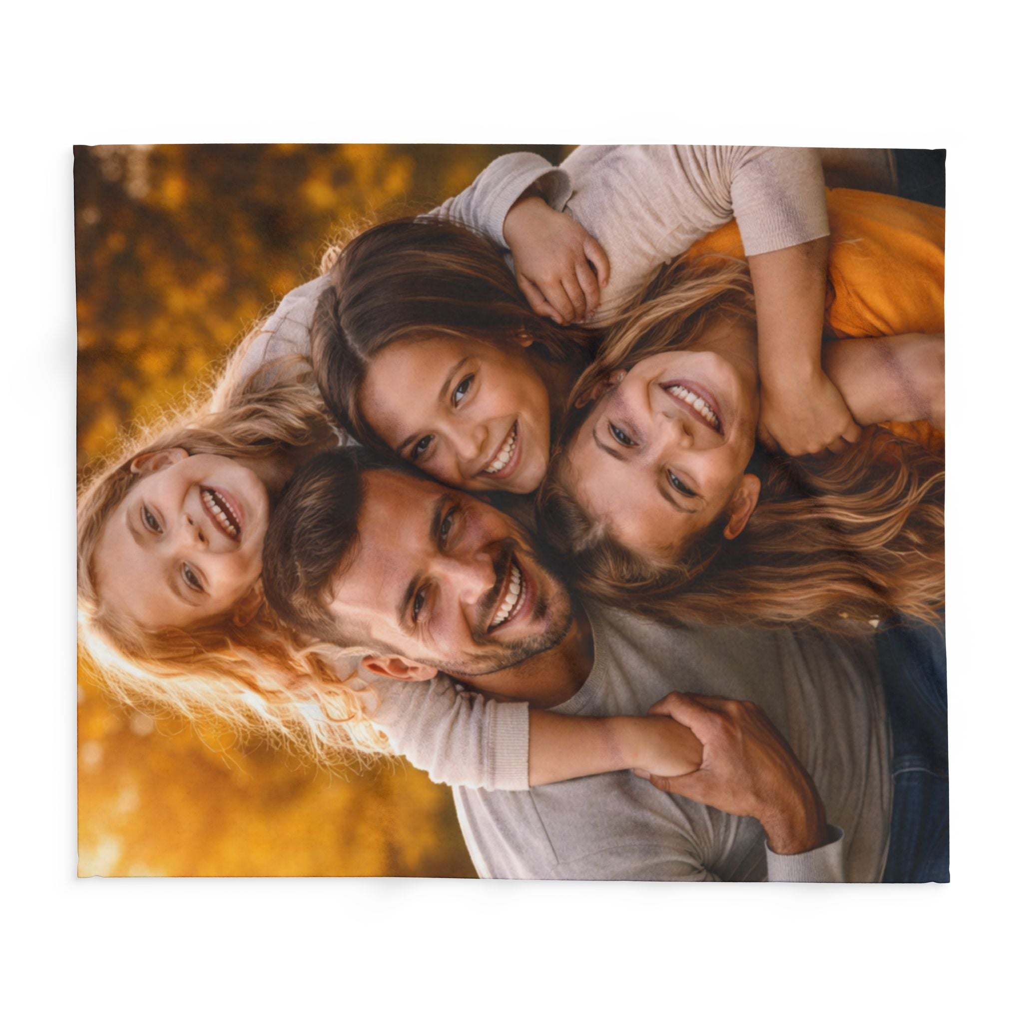 Family of four lying on their backs with a blurred autumn background